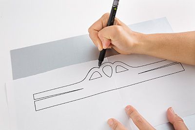 厚紙の裏面に型紙を置いて、型紙のラインに沿ってボールペンでスジをつける。