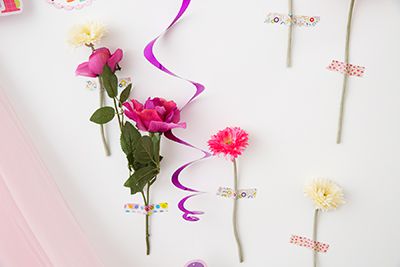 造花を１本ずつ、マスキングテープで壁に貼り付けるだけのお手軽デコ。カラーをピンク＆ホワイトに絞ったり、同じ種類の花を選べば、ランダムに貼っても統一感をキープ。造花は100円均一で可愛いものが手に入ります。