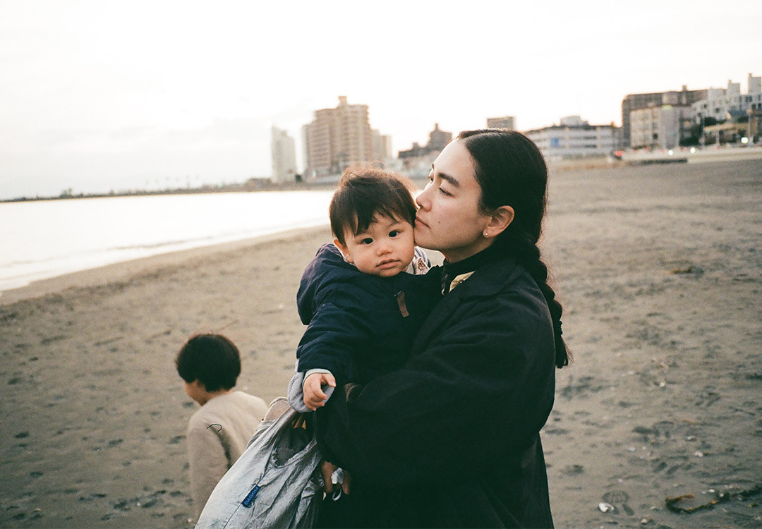 海岸沿いでお散歩をしている風景。ママと男の子と赤ちゃん。