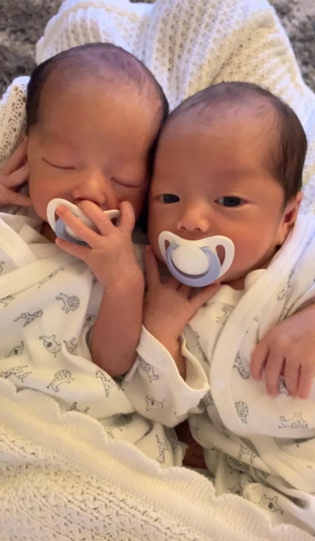 双子の男の子の赤ちゃんがおしゃぶりを咥えて並んで寝ている